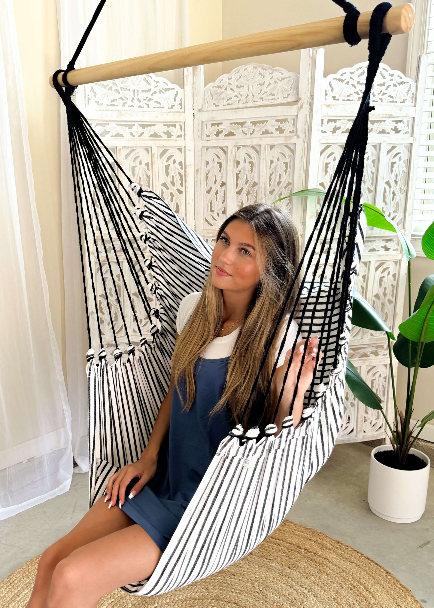 woman sitting on a black and white hammock chair