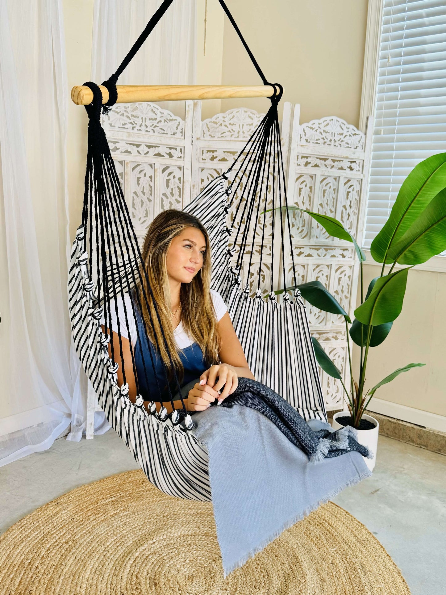 woman sitting on a black and white hammock chair indoors