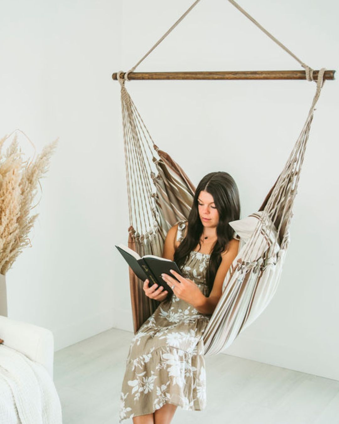 woman on a brown hammock chair swing reading a book