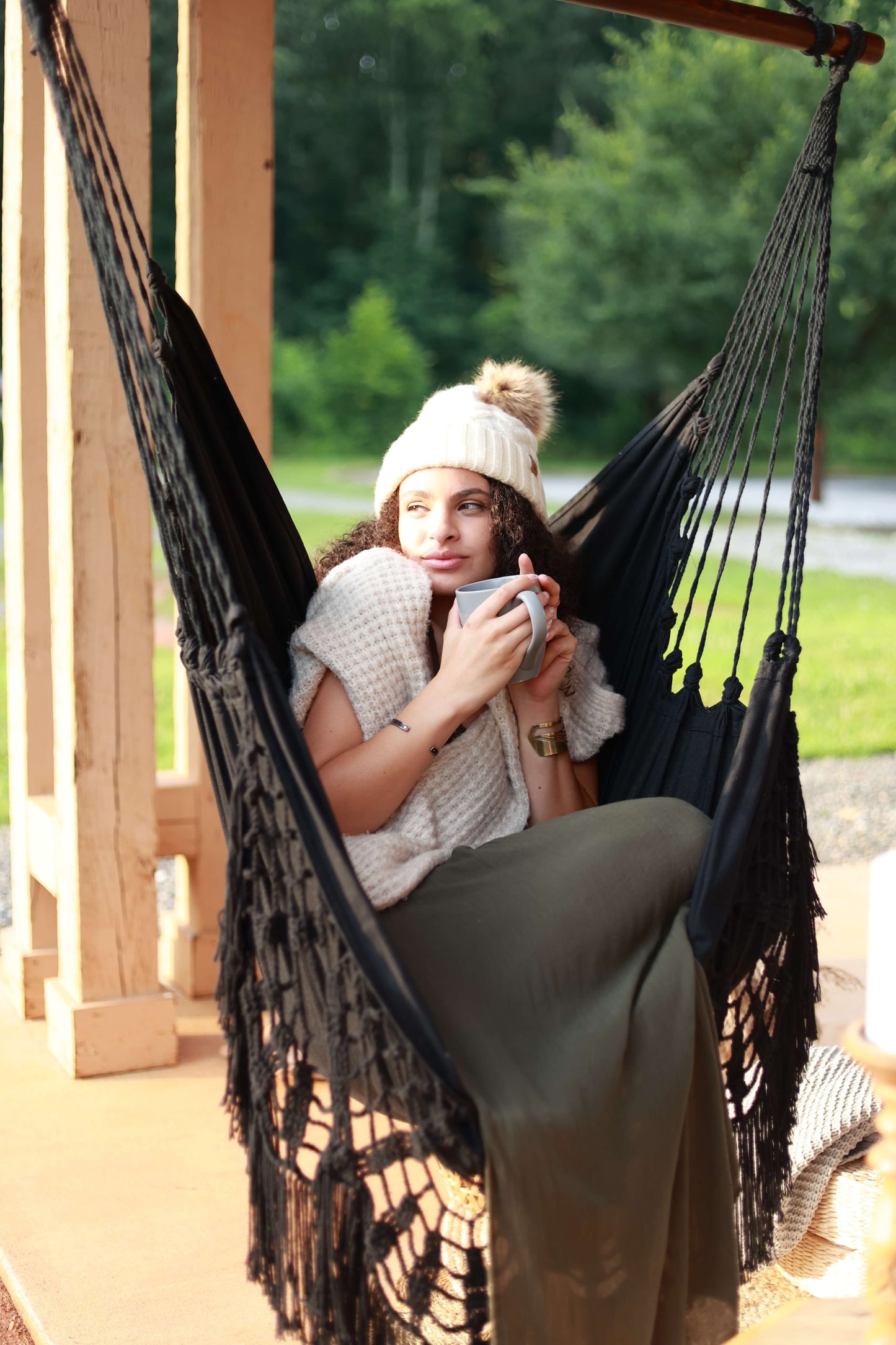 Woman holding a cup sitting on a black Crochet Hammock Chair