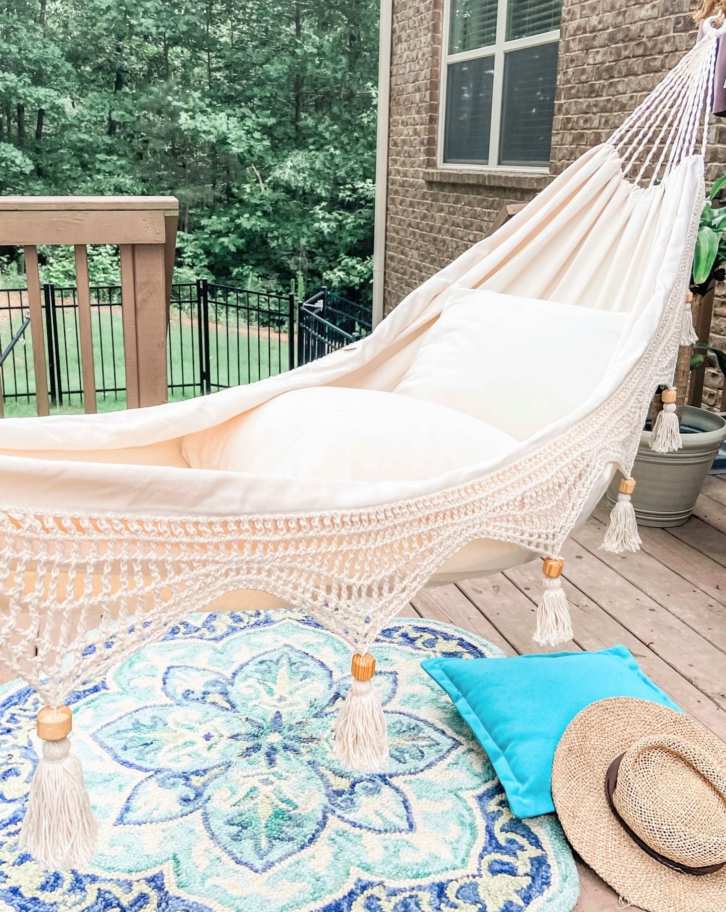 boho crochet fringe hammock with a blue rug on a porch