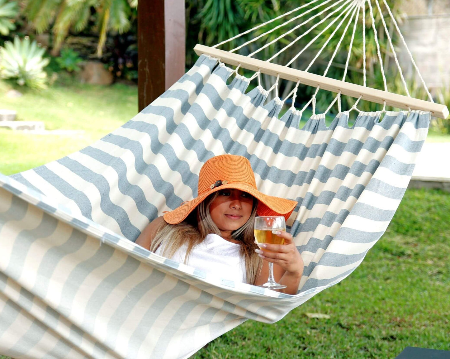 woman drinking on a coastal beach resort hammock