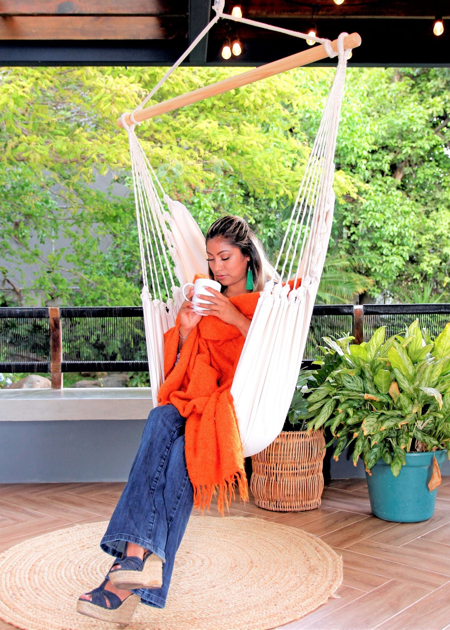 woman with orange blanket sitting on a Hanging hammock chair swing