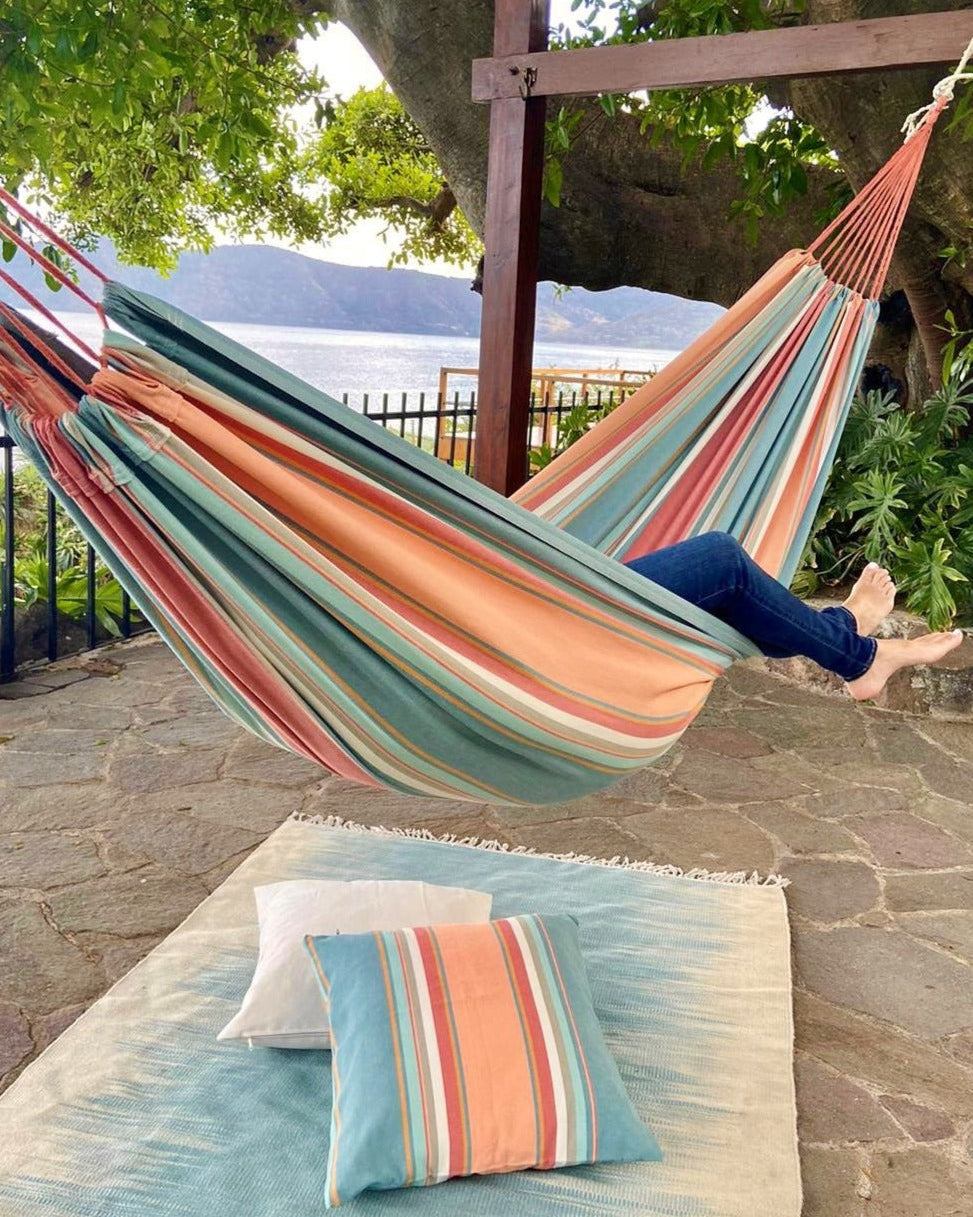 striped pink and light blue canvas hammock under a tree