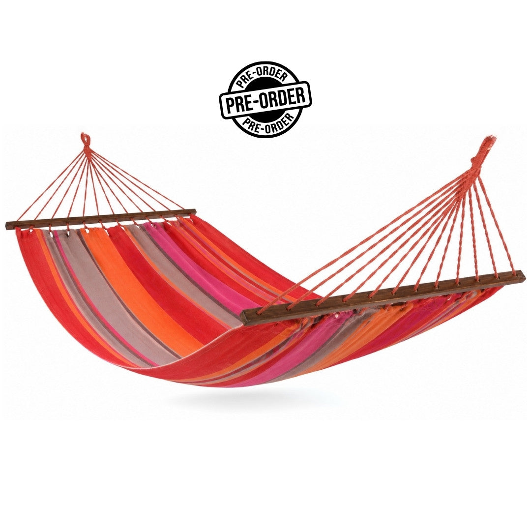 A striped fabric hammock with wood spreader bars with red, orange, pink, and against a plain white background.