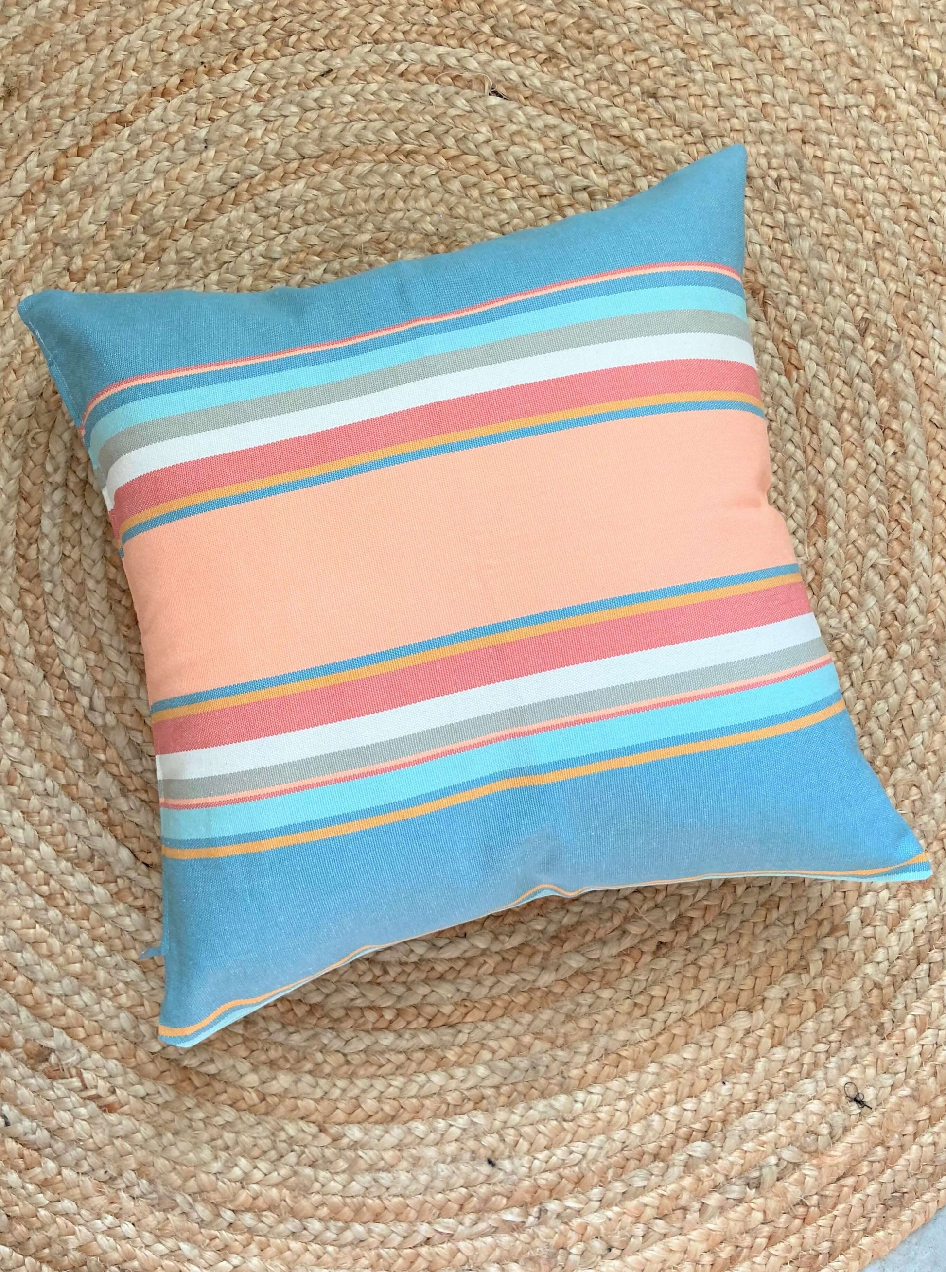 pastel striped pink pillow laying on a jute rug