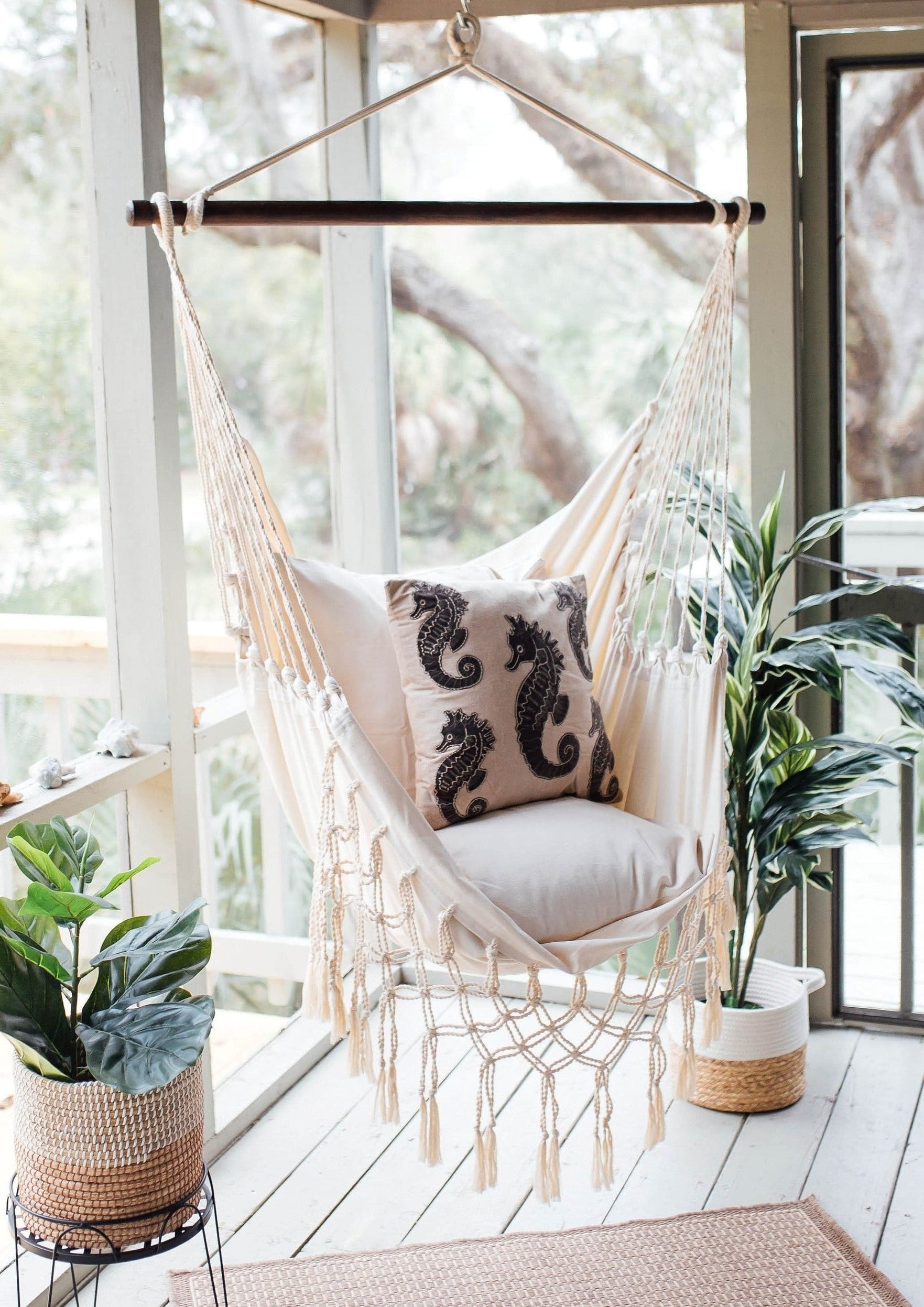 macrame hanging swing chair on a screened porch with a seahorse pillow  and plants