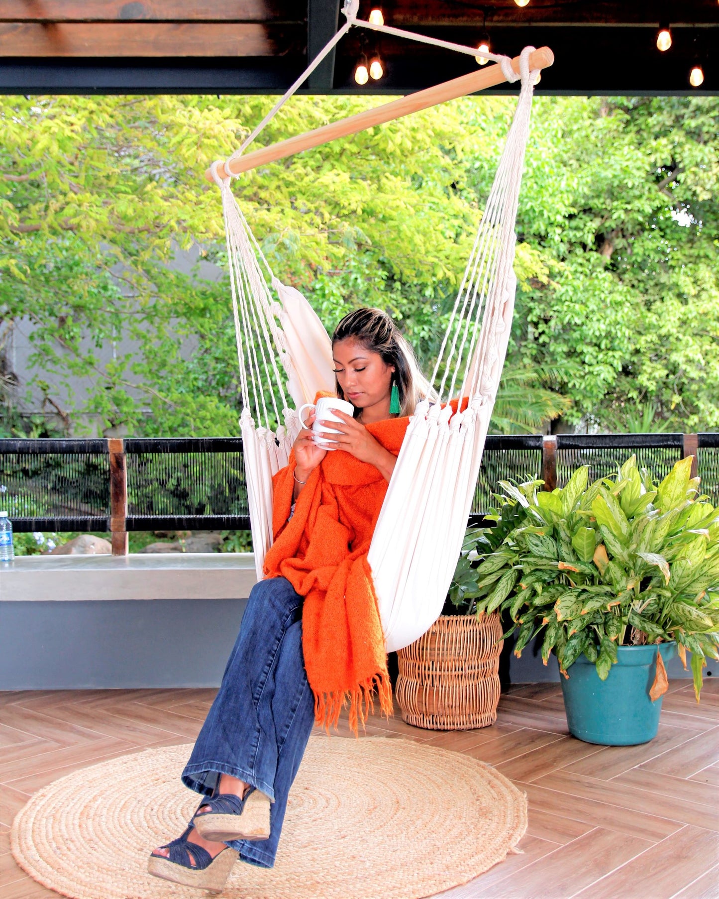woman with orange blanket sitting on a Hanging hammock chair swing