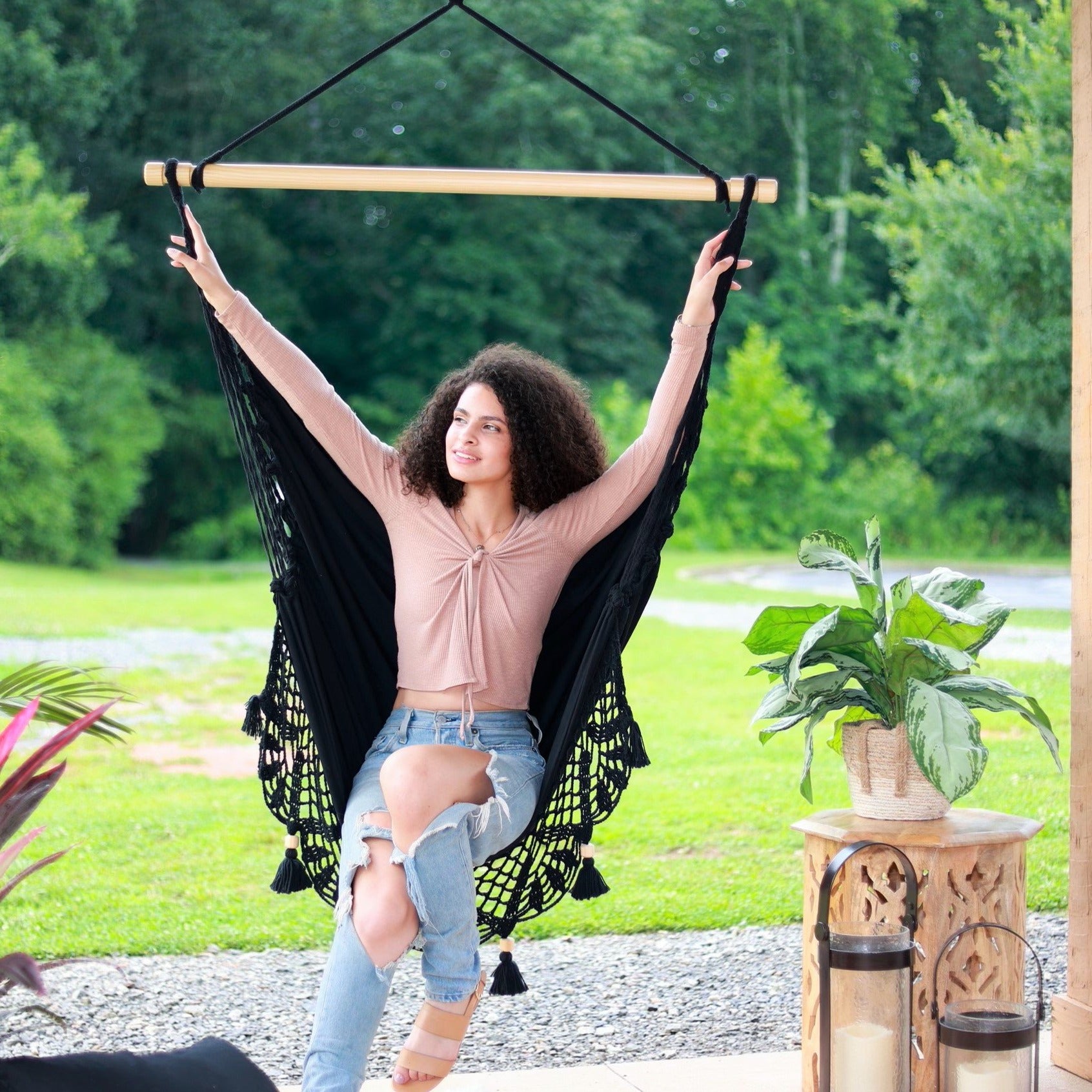 woman on a black macrame hammock swing chair with open arms