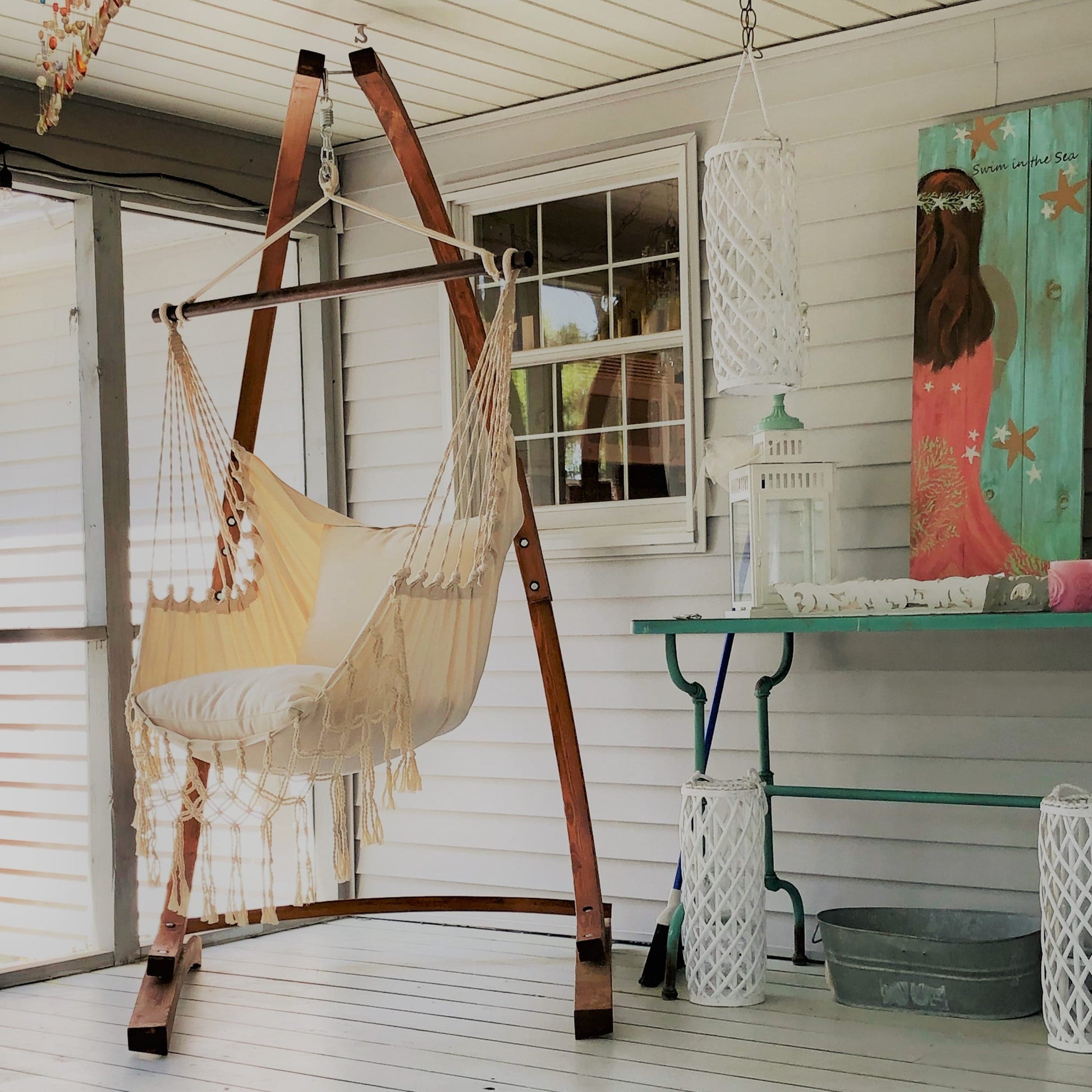 White Macrame hammock swing chair on a wooden chair stand  in a covered patio'
